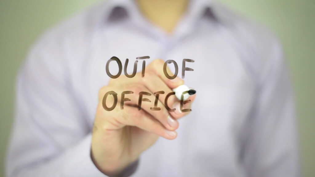Mann schreibt auf eine Glaswand "out of office"
