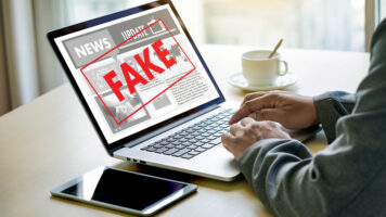 fake news - man reading fake news on laptop