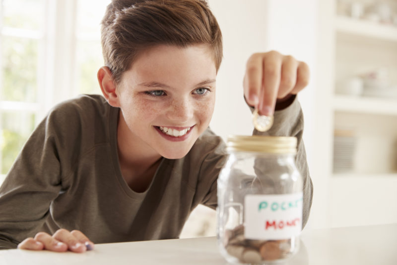 Junge spart Geld in einem Gurkenglas