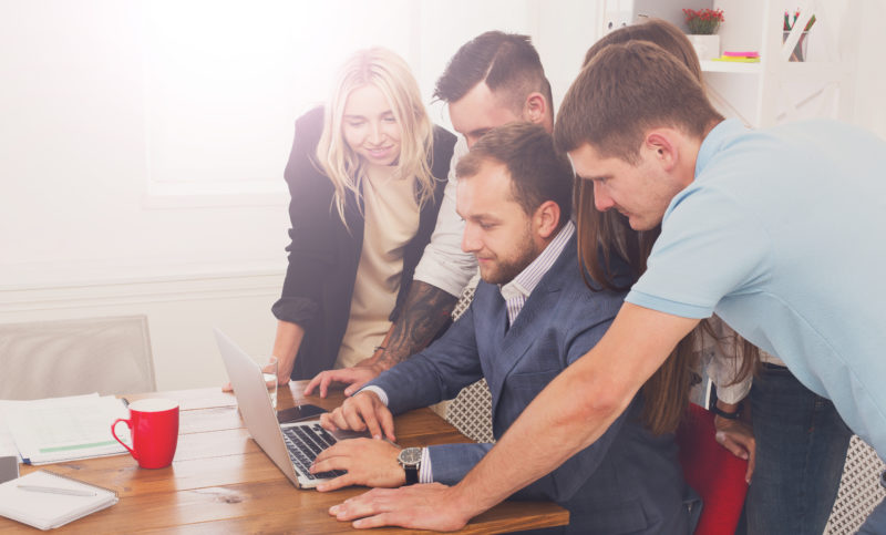 Happy business people team together look at laptop in office